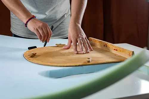 Mit einem Filzstift eine Linie auf den Schaumstoff für die Stuhlsitzpolsterung zeichnen, bevor dieser zugeschnitten wird.